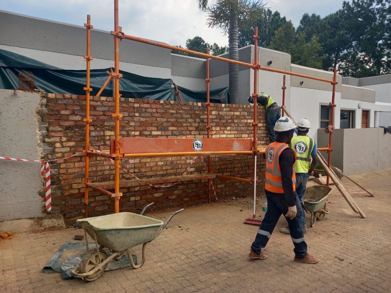 two uniformed workers repairing a durawall using a scaffold